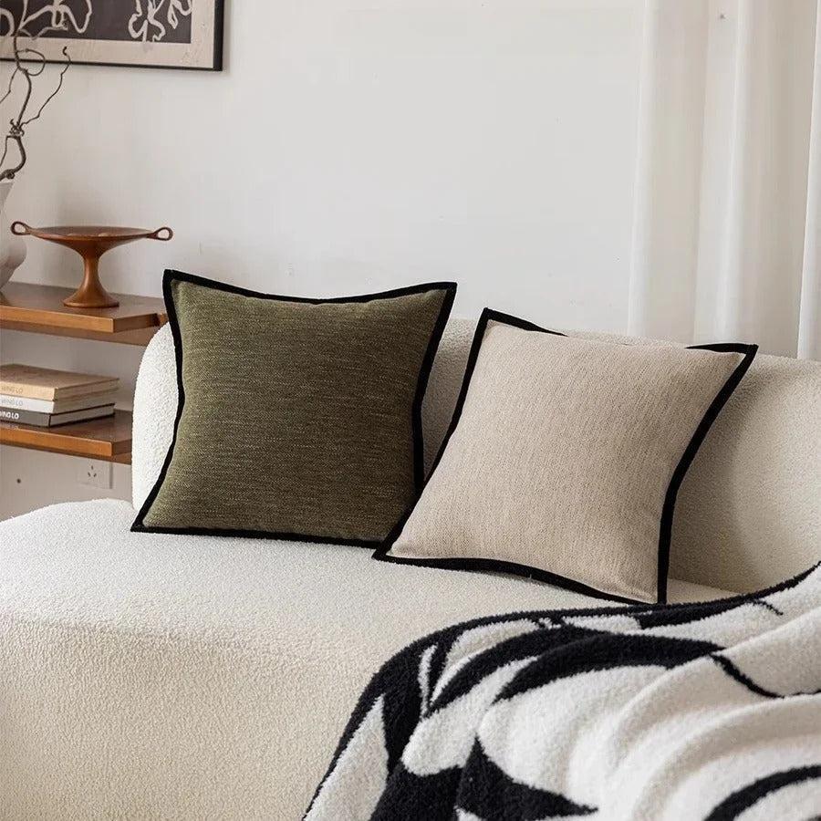 Cushion cover with a black border in retro green on a sofa